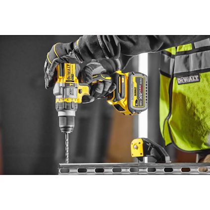 En person håller i en gul borrmaskin från Dewalt och borrar i en metallbalk.