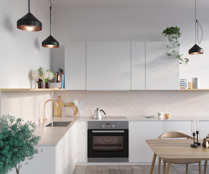 Modernt kök med vita skåp, inbyggd ugn och diskho. Tre hängande lampor och en trämatplats. Gröna växter som dekoration.