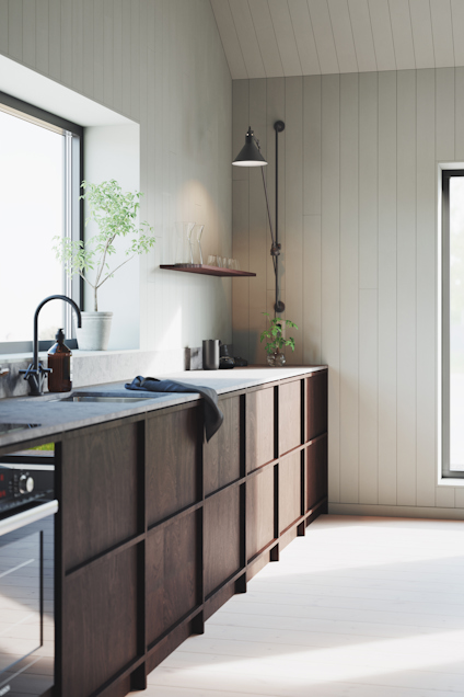 Modernt kök med träpanelväggar, mörka skåp och vägglampa. Fönster ger naturligt ljus.
