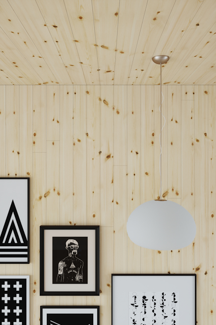 Ljusa träpaneler på vägg och tak, flera svartvita tavlor och en rund hängande lampa.