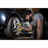 Person använder en borrmaskin för att lossa ett däck på en bil i ett garage.