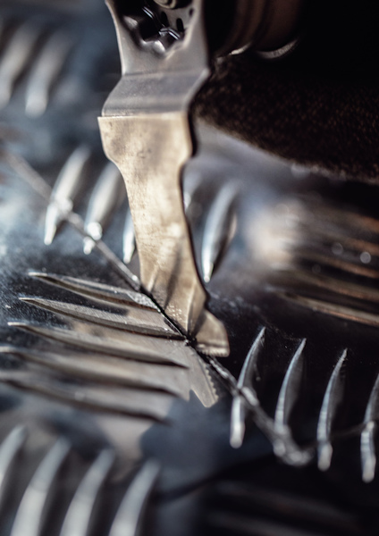 Metalltandad skärblad nära korrugerat metallmaterial.