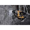 Person i arbetskläder borrar i en rå stenmur med en gulsvart Dewalt borrmaskin.