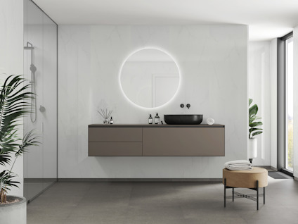 Modernt badrum med vägghängd brun hylla, rund spegel med belysning, svart handfat och stora fönster.