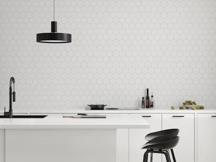 Modernt kök med hexagonalt kakel, svart lampdesign och detaljer. Svarta stolar vid vit köksö.