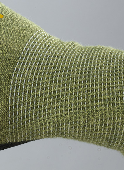 Grön stickad textil med vita ränder och textur.