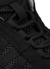 Svart sneakers med nät och snörning i närbild.