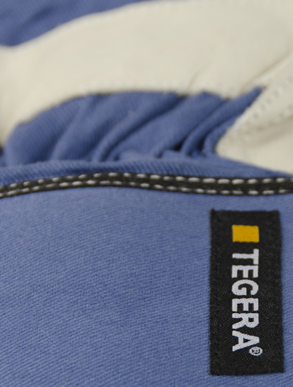 Blå handske med vit insida, märkt "TEGERA" i svart rektangel med gul kvadrat bredvid texten.