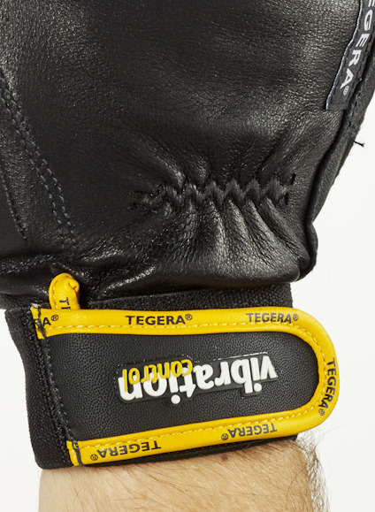 Svart handske med gul kant och texten "vibration comfort" samt "TEGERA" i vitt.