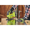 En person med handskar använder en grön Ryobi sticksåg för att såga i en metallplåt.