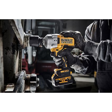 Person som använder en gul och svart DEWALT 18V XR-skruvdragare på en metallbult.