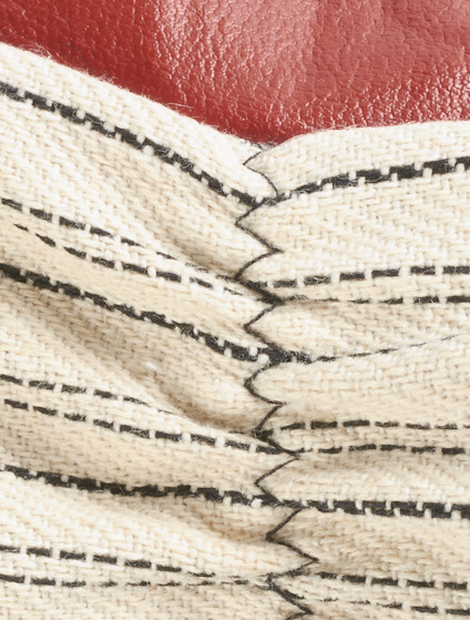Närbild av ett texturerat material med ränder, ihopkopplat med ett rött konstläder.