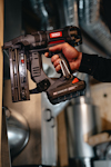 Person som håller en svart batteridriven spikpistol med märkning "Senco" och "18V".