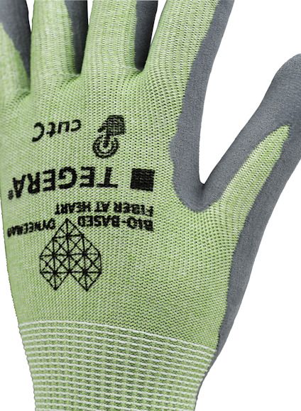 Grön handske med grå förstärkningar, märkning "TEGERA®", "CUT C", "FIBER A† HERN", "BIO-BASED".