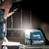 Hand som håller en Makita XGT borrmaskin ovanför ett Makita 40V Max XGT 2.5Ah batteri på en metallisk yta.