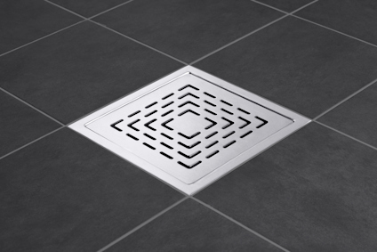 Kvadratiskt golvbrunnslock i rostfritt stål med diagonala spår på mörkgrått kakelgolv.