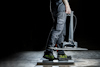 Person in workwear steps on pressure-testing device in a dimly lit space.