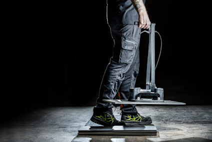 Person in workwear steps on pressure-testing device in a dimly lit space.