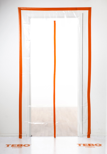 Transparent plastöverdrag med orangefärgad dragkedja och ram, placerat över en dörröppning; märkt med "TEBO".