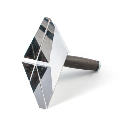 Metallisk fogbricka med triangulärt huvud och ett mörkt handtag.