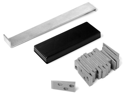 En stålskena, en svart plastblock, och staplade grå distanskilar mot en vit bakgrund.