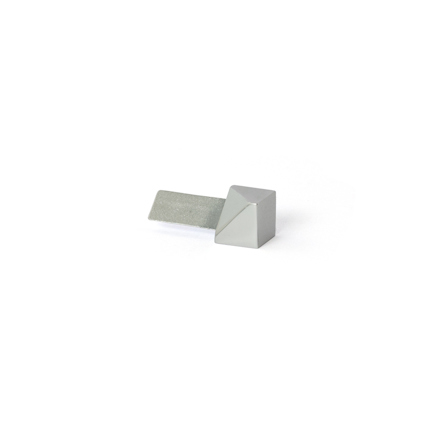 Ett kubformat, blankt metallföremål med en triangulär topp, intill en platt, rektangulär metallbit.
