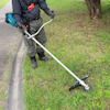 Person trimmer gräs vid en trottoarkant med en blå och svart grästrimmer.
