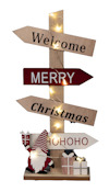 Trästolpe med ljussatta skyltar som säger "Welcome", "Merry", "Christmas" och "HO HO HO". dekorativ tomte och presenter längst ner.