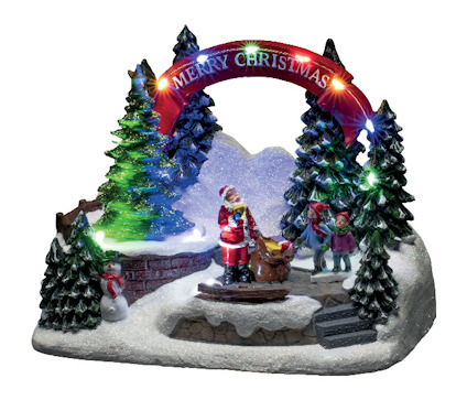 Juldekoration med lysande "Merry Christmas"-skylt, granar och tomtefigur omgiven av barn i ett vinterlandskap.