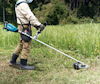 Person som använder en grästrimmer i en gräsfylld utomhusmiljö.
