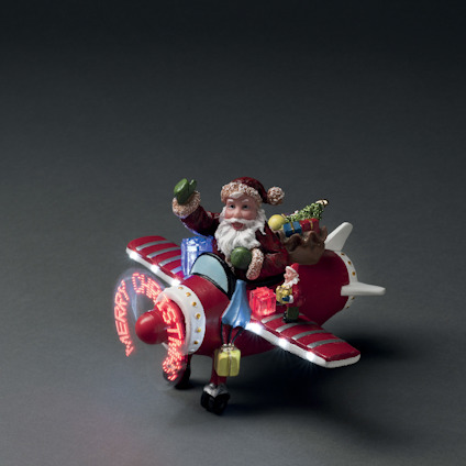 Tomtefigur i rött flygplan med tändande LED-lampor, håller julklappar.