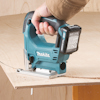En person håller i en blå sladdlös Makita sticksåg som skär i plywood.