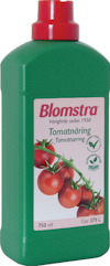 Grön flaska med röd kork, etikett med tomater och texten "Blomstra Tomatnäring".