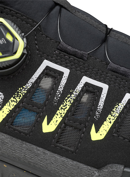 Svart sko med gula och vita detaljer, synlig BOA-dial och ventilation i ovandelen.