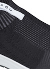 Svart stickad sneaker med vit etikett och synlig textur.