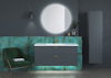 Modern bathroom with green chair, illuminated round mirror, teal wall with floating sink unit, and tall cabinet.