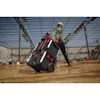 Person in work gear pulling a wheeled toolbox on a construction site. Steel framework visible.