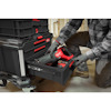 Person in workwear removes power tool from black plastic storage box with red handle and drawers in a workshop.