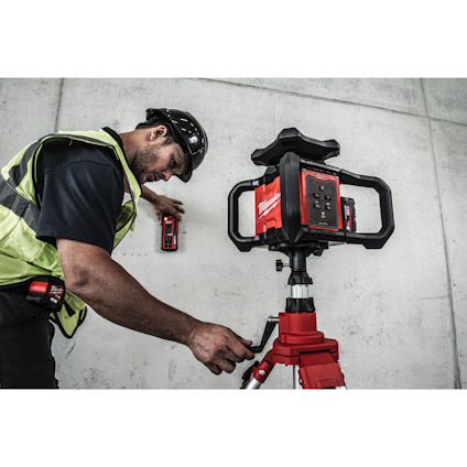 Person i skyddsutrustning justerar en laserscanner på ett stativ framför en betongvägg.