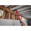 Hand holding a red tool accessing pipes above an unfinished ceiling with exposed insulation and wooden beams.