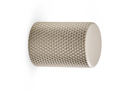 Knopp i metall med sandfärgad yta och räfflad textur.