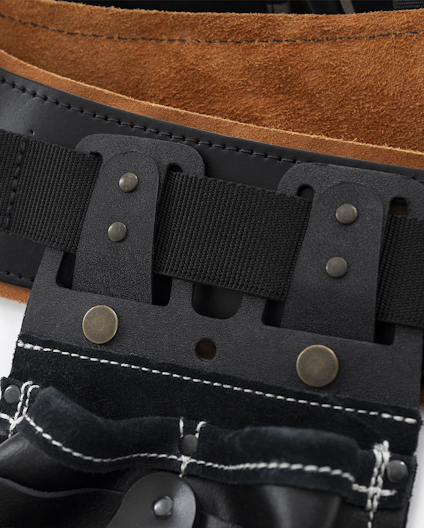 Närbild på del av verktygsbälte i läder och textil med metallnitar och sömmar.