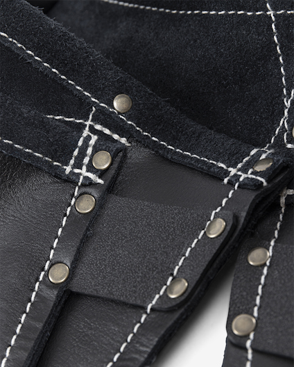 Svarta förstärkta skyddshandskar med vita sömmar och metallnitar.