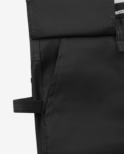 Svart vadderad textil med sömmar och rem; del av större objekt.