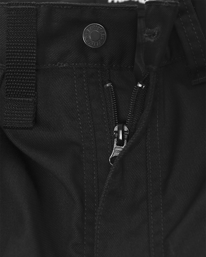 Svart tyg med synliga sömmar, blixtlås och en metallknapp med texten "Carhartt".