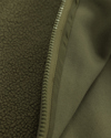 Olivgrönt tyg med dragkedja i mitten, ena sidan har en slät yta och den andra sidan har en texturerad yta.