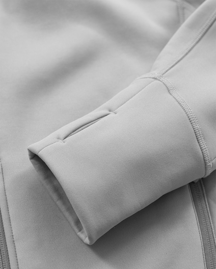Grå tröja med lång ärm och tumhål, sydd med synliga sömmar.