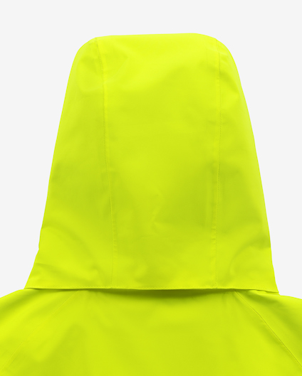 Gul huva på en jacka, sedd bakifrån, mot en ljusgrå bakgrund.