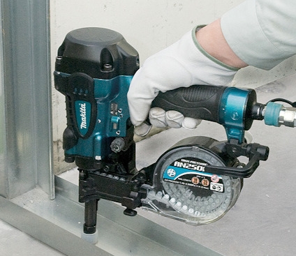 Person använder en Makita spikpistol för att fästa metallramar mot ett golv.