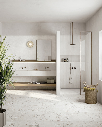 Modernt badrum med dubbla handfat, dusch med glasvägg, korg och gröna växter. Ljusa väggar och terrazzo-golv.